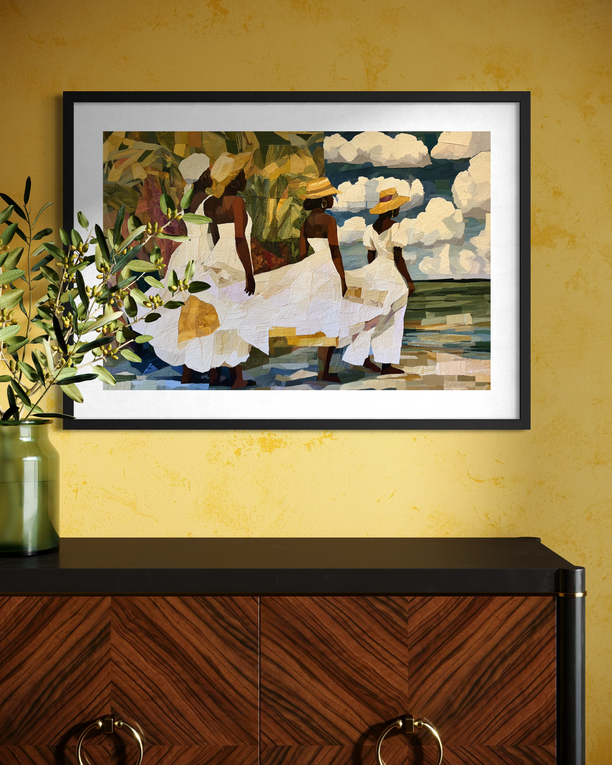 Framed fine art print depicting Afrocentric Gullah Geechee women dressed in white faux quilt-style patter dresses celebrating Black Low Country coastal heritage, African American ancestry, cultural traditions, family, community, and life rooted by the sea.  Displayed on an yellow wall above a dark panel console cabinet.