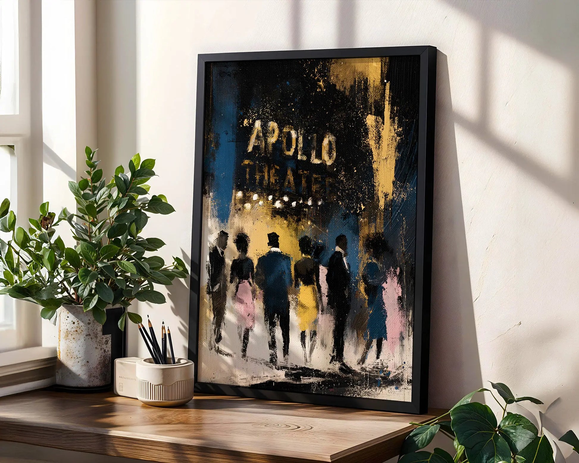 A framed art print leaning on a wooden windowsill in a bright room. The print features an abstract painting of figures walking towards the 'APOLLO THEATER' in distressed gold lettering.