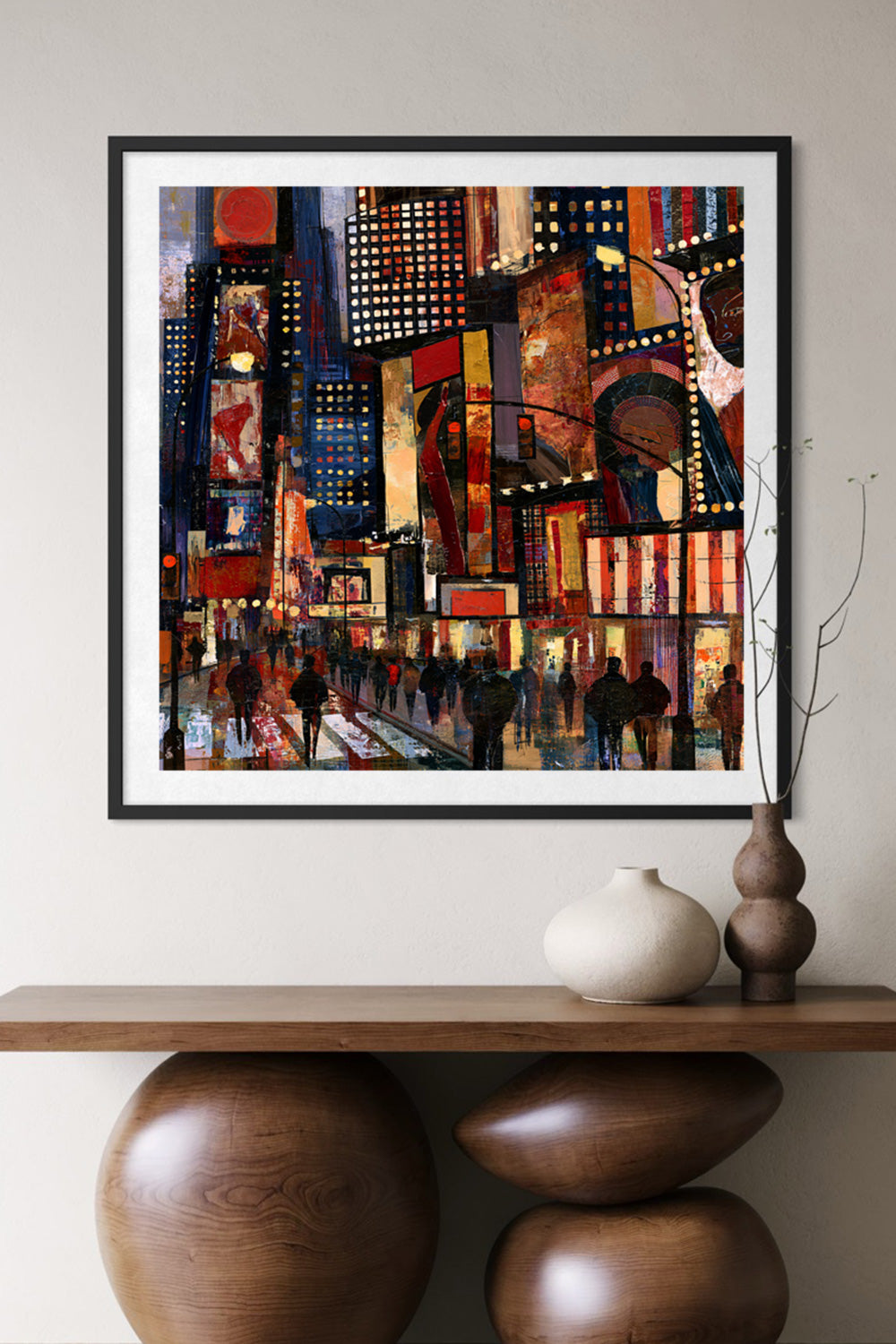 A framed abstract painting of a bustling Times Square at night hangs on a light beige wall above a wooden console table with decorative ceramic vases.