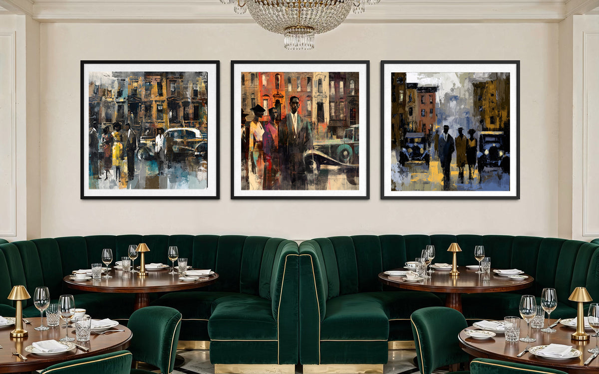 A staged restaurant interior with three framed Harlem vintage city street art prints hanging above a curved dark green velvet booth and tables set with glassware and lamps.