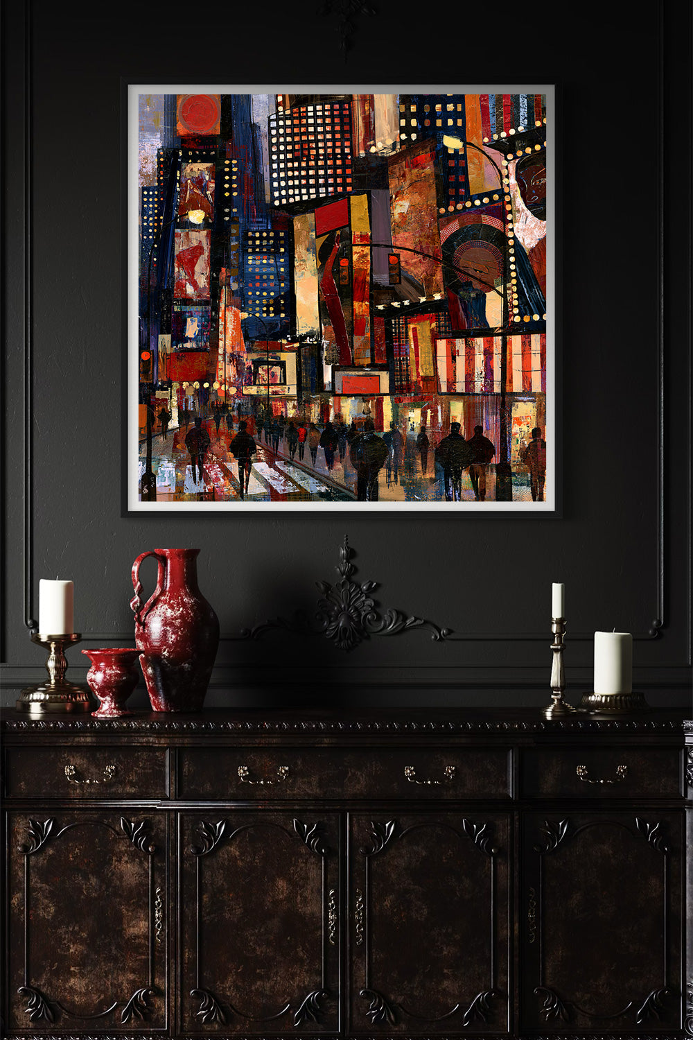 A framed abstract painting of a city street with colorful buildings and figures, displayed on a dark wall above a decorative dark wood console table with candles and a red vase.